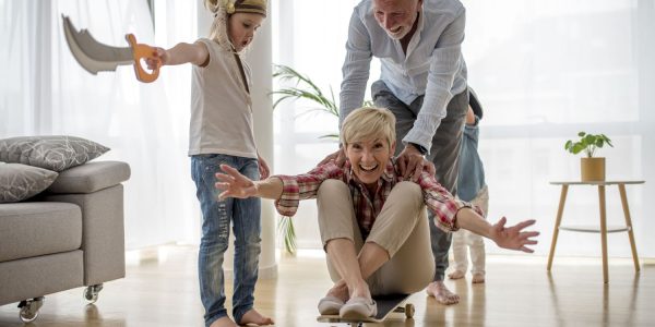 caucasian-grandfather-pushing-grandmother-skateboard-inside-with-grandson-wearing-pirate-costume