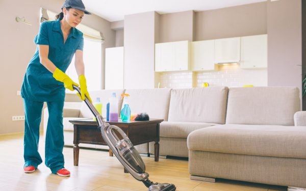 girl-is-walking-studio-apartment-cleaning-floor-with-vacuum-cleaner-she-holds-it-with-both-hands-woman-is-alone