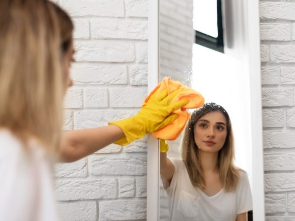 side-view-woman-cleaning-mirror-with-cloth
